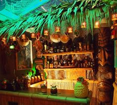 a room filled with lots of green plants and lights on the ceiling, along with shelves full of bottles