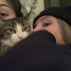 two women and a cat are looking at the camera while one woman is covering her face