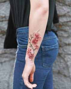 a woman's arm with flowers on it and her hand in the other direction