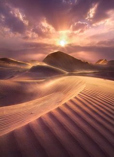 the sun is setting over sand dunes in the desert