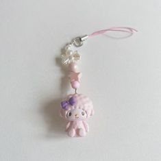 a hello kitty keychain hanging on a white surface with a pink ribbon around it