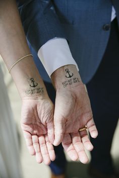 two people holding hands with tattoos on them