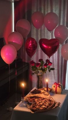 a table topped with a pizza and balloons