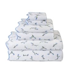 four towels stacked on top of each other with blue flowers and leaves in the middle