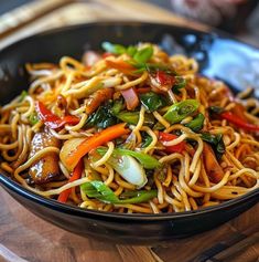 a black bowl filled with noodles and vegetables