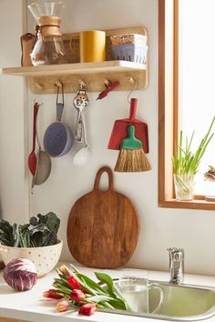 a kitchen counter with various pots and pans hanging on the wall above it is a wooden cutting board