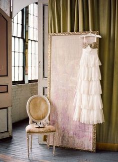 a dress hanging on a hanger next to a chair