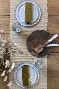 the table is set with plates, silverware and green napkins on top of it