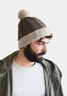 a man with a beard wearing a knitted beanie and looking at his cell phone