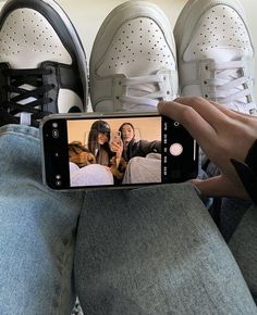 a person taking a selfie with their cell phone in front of two pairs of shoes