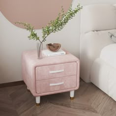 a pink nightstand next to a bed with a plant on it and a white pillow