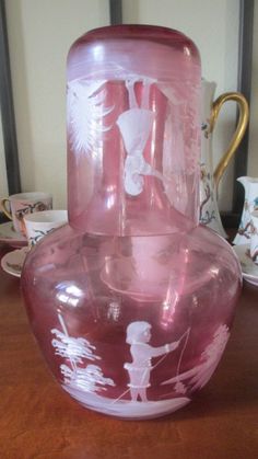 a pink glass vase sitting on top of a wooden table