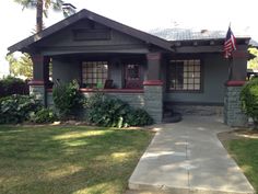 a gray house with an american flag on the porch