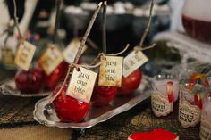 some apples are sitting on a silver plate with tags hanging from them that say just one bite