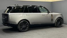 an suv is parked in a room with grey walls and black rims on it