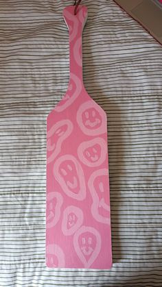 a pink cutting board sitting on top of a bed next to a striped wallpaper