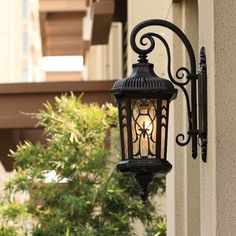 an old fashioned street light hanging from the side of a building with trees in the background