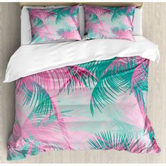 a bed with pink and green palm leaves on it, next to a white pillow