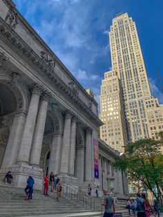 people are walking up and down the stairs in front of a building with tall buildings