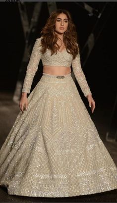 a model walks the ramp in a white lehenga and crop top with sequins