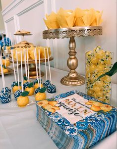 a table topped with lots of yellow and blue desserts on top of a white table cloth