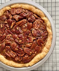 a pecan pie sitting on top of a metal pan next to a wire rack