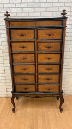 an old wooden dresser sitting on top of a hard wood floor next to a brick wall