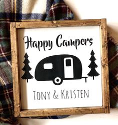 a wooden sign that says happy campers and a trailer with pine trees on it