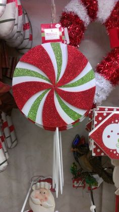 a candy cane ornament is hanging from a christmas decoration pole in front of other holiday decorations