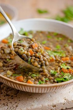 a spoon full of lentula soup with carrots and parsley