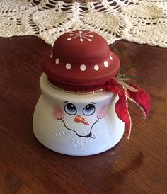 a ceramic snowman with a red hat on it's head sitting on a table