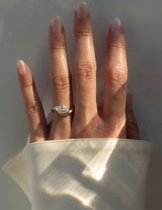 a woman's hand with a diamond ring on top of her left hand, against a white background