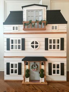 a doll house with black shutters and white trim