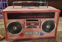 an old fashioned pink radio with speakers on the front and side, sitting on a carpeted floor