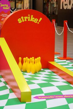 there are some yellow bowling pins on the checkered tablecloth and in front of a red sign that says strike