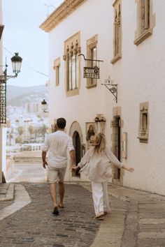 two people are walking down the street holding hands