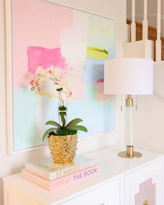 a potted plant sitting on top of a white table next to a book and lamp