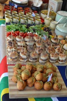 an assortment of appetizers are displayed on a wooden board at a buffet table