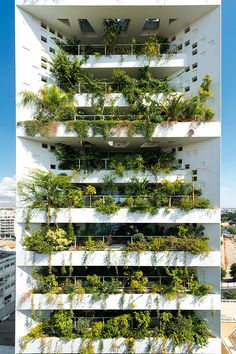 a tall white building with plants growing on it's sides and balconies