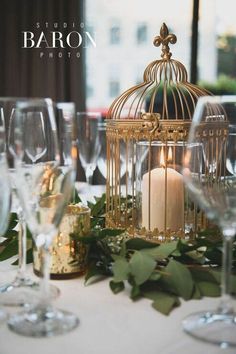 a birdcage filled with candles sitting on top of a table next to wine glasses