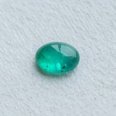 a green oval shaped gems sitting on top of a white surface