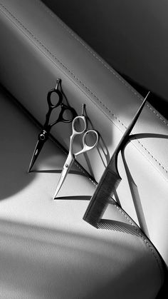 two pairs of scissors sitting on top of a white bag