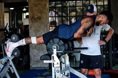 two men are doing exercises on the same machine as they stand in front of each other