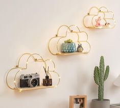 three gold heart shaped shelves on a white wall next to a potted cacti