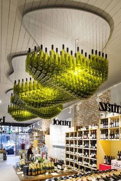 a store filled with lots of green wine bottles hanging from the ceiling and chandelier