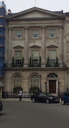 two cars parked in front of an old building with scaffolding on the windows