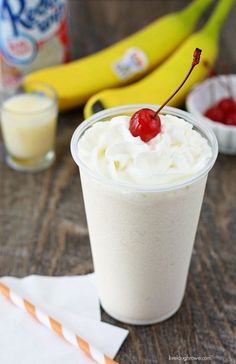 there is a drink with whipped cream and a cherry on the top, next to bananas