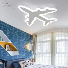 a bed room with a neatly made bed and a ceiling light that is shaped like an airplane