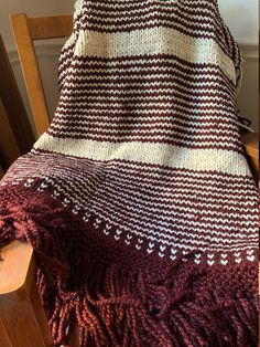 a brown and white blanket sitting on top of a wooden chair