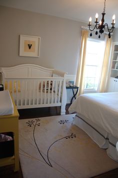 a baby's room with a white crib and chandelier